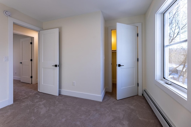 unfurnished bedroom with a baseboard radiator and dark carpet