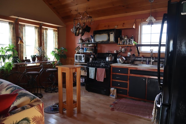 kitchen featuring vaulted ceiling, pendant lighting, sink, wood ceiling, and black appliances