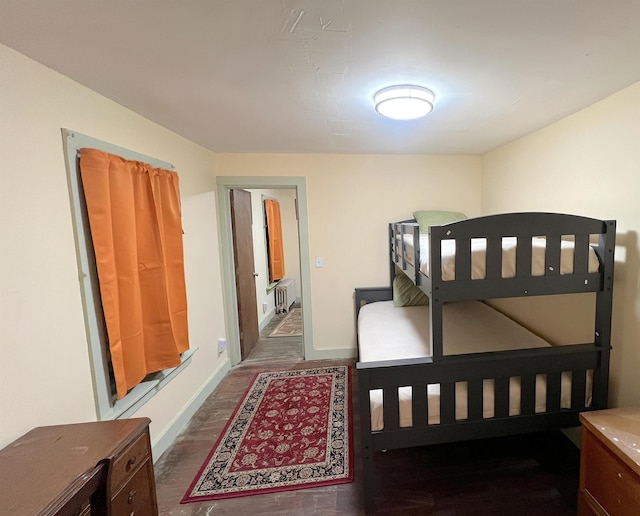 bedroom with radiator heating unit and dark wood-type flooring