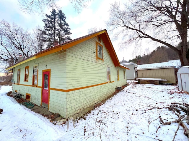 view of snowy exterior featuring a shed