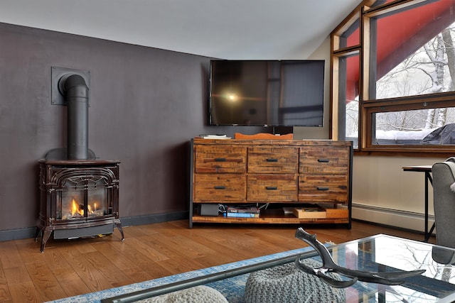 interior space with wood-type flooring, a wood stove, and baseboard heating