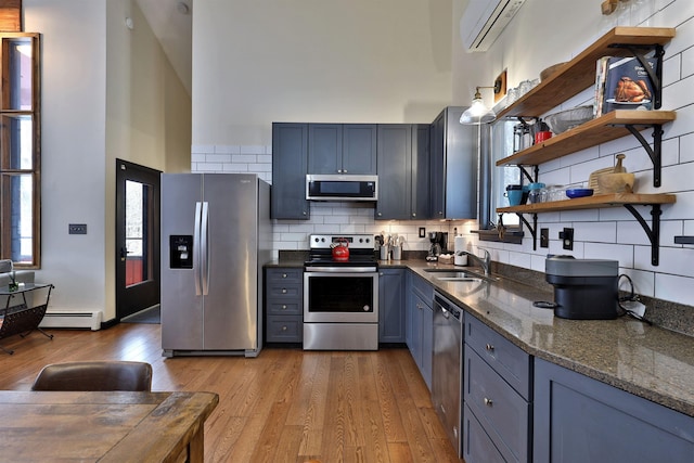 kitchen featuring light wood-type flooring, tasteful backsplash, stainless steel appliances, a wall unit AC, and sink