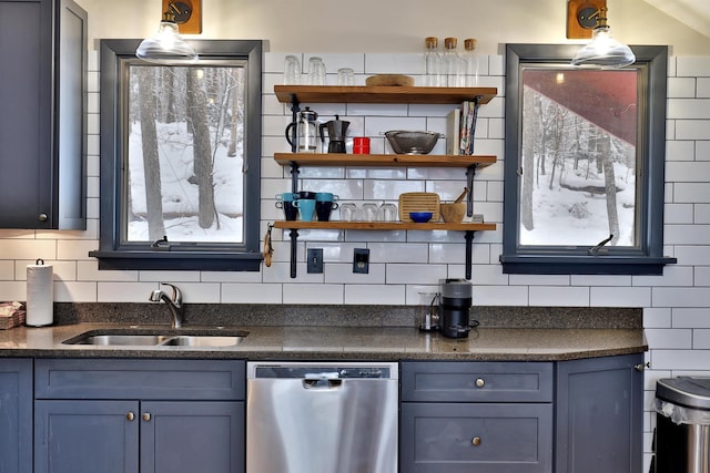 kitchen featuring backsplash, stainless steel dishwasher, sink, blue cabinetry, and hanging light fixtures