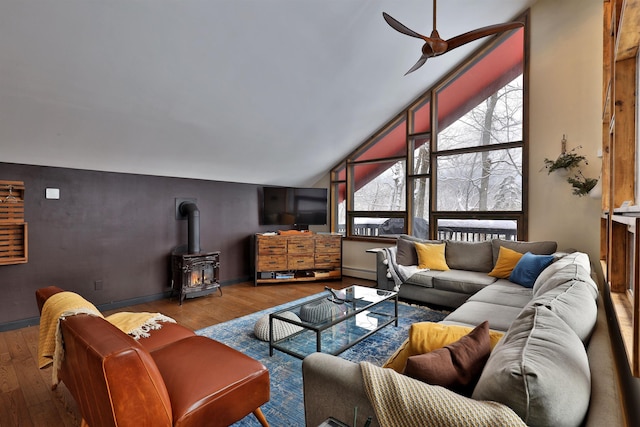 living room featuring baseboard heating, light hardwood / wood-style flooring, a wood stove, and ceiling fan