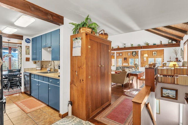 kitchen featuring blue cabinetry, sink, light tile patterned flooring, and stainless steel dishwasher