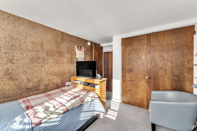 bedroom with carpet floors, a closet, and wooden walls