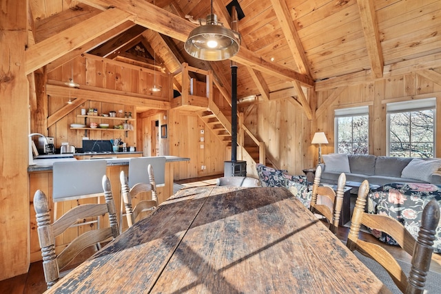 dining space featuring high vaulted ceiling, beam ceiling, wooden ceiling, and wood walls