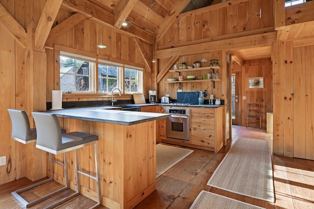 kitchen featuring wooden walls, oven, kitchen peninsula, and light wood-type flooring