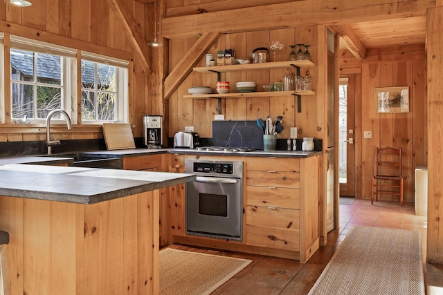 kitchen with wooden ceiling, stainless steel appliances, sink, and wood walls