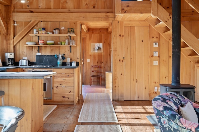 kitchen featuring wood walls, light brown cabinetry, light hardwood / wood-style floors, and a wood stove