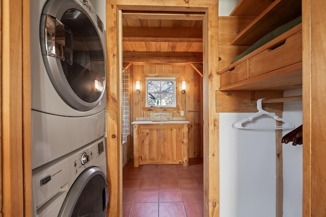 laundry room with tile patterned flooring, stacked washing maching and dryer, wood ceiling, and wooden walls