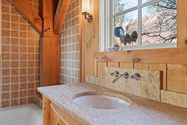 bathroom with vanity, a bath, and a healthy amount of sunlight