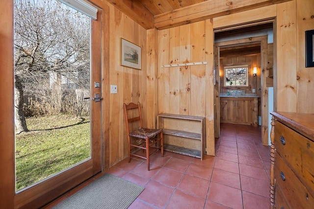 doorway featuring wooden ceiling, tile patterned flooring, and wood walls