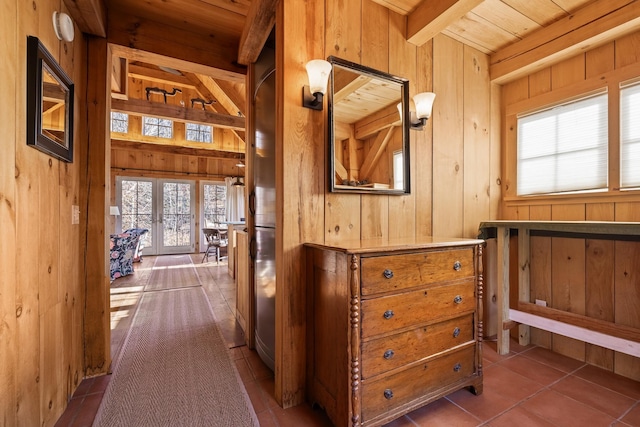 corridor featuring wooden walls, tile patterned flooring, wood ceiling, beam ceiling, and french doors