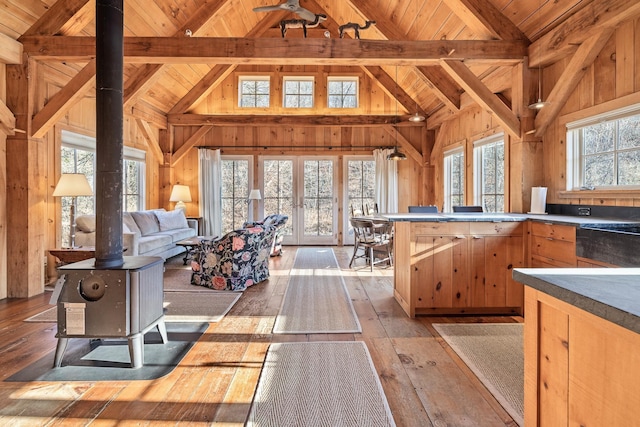 kitchen featuring wood ceiling, a wood stove, wooden walls, beamed ceiling, and light hardwood / wood-style floors