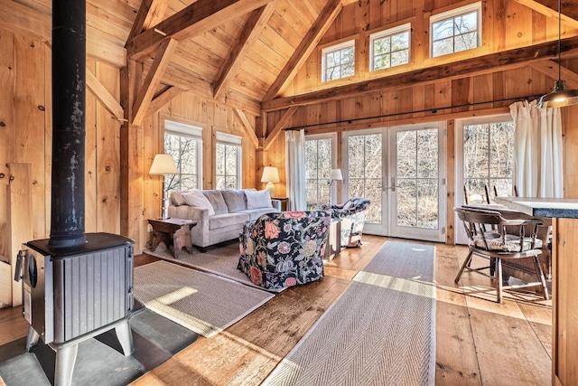 interior space featuring lofted ceiling with beams, french doors, wooden ceiling, and a wood stove