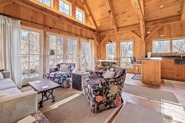 living room featuring wood ceiling, a healthy amount of sunlight, beam ceiling, and wood walls