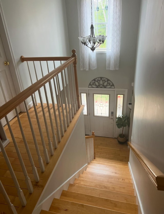 stairs with hardwood / wood-style floors and a notable chandelier