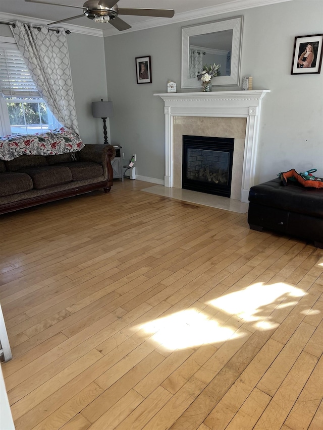 living room with crown molding, a high end fireplace, ceiling fan, and light wood-type flooring