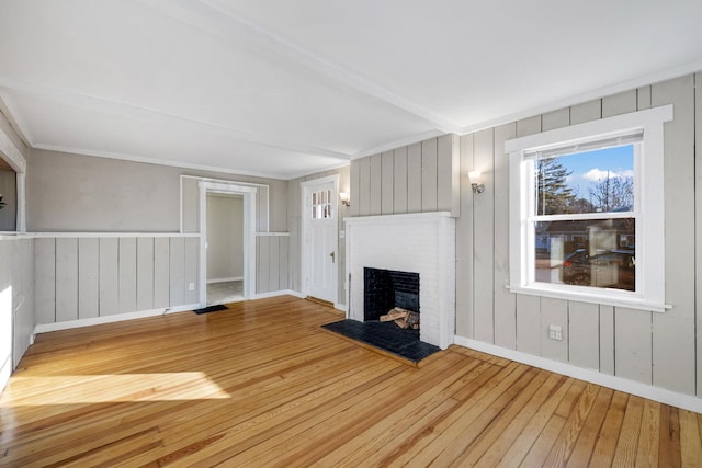 unfurnished living room with a fireplace, wood-type flooring, and beamed ceiling