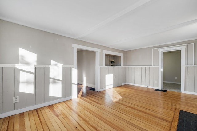 spare room with beam ceiling and hardwood / wood-style flooring