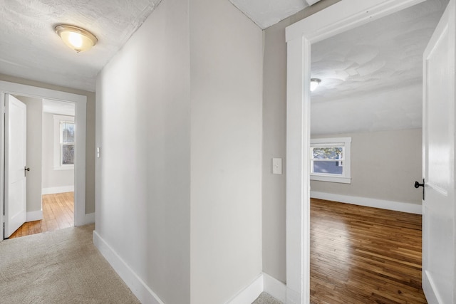 corridor with hardwood / wood-style floors, a textured ceiling, vaulted ceiling, and plenty of natural light