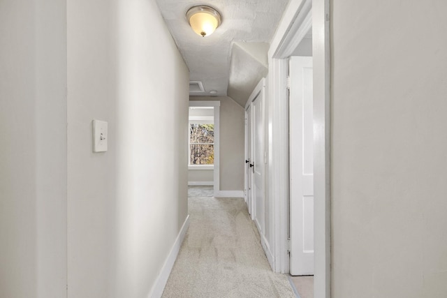 hall featuring lofted ceiling, a textured ceiling, and light carpet