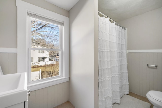 bathroom with wooden walls, a shower with shower curtain, and toilet