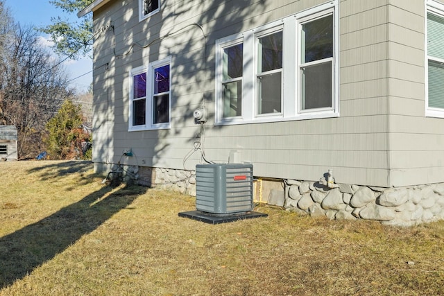 view of property exterior featuring central air condition unit and a yard