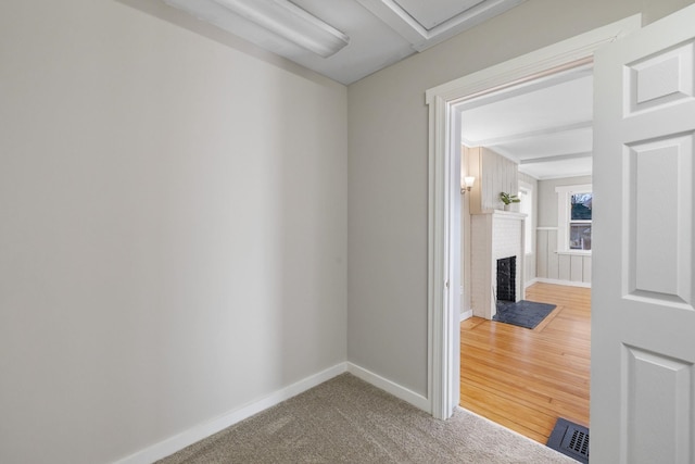 carpeted spare room featuring a brick fireplace