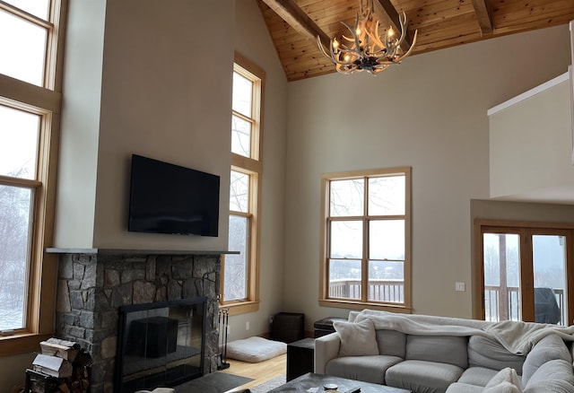 living room featuring beam ceiling, a wealth of natural light, a notable chandelier, a fireplace, and wood ceiling