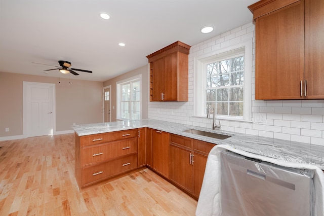 kitchen featuring kitchen peninsula, tasteful backsplash, sink, dishwasher, and light hardwood / wood-style floors