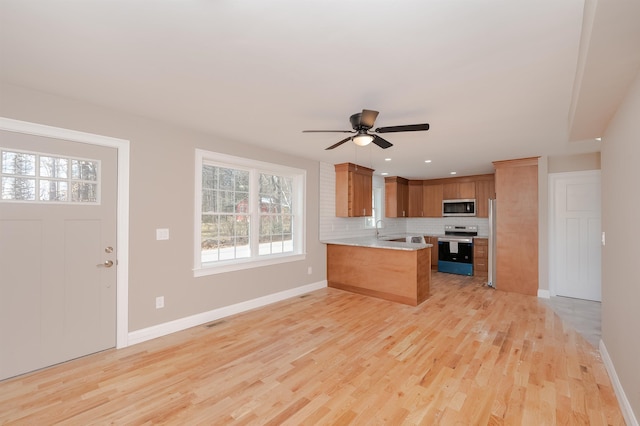 kitchen featuring tasteful backsplash, kitchen peninsula, plenty of natural light, and appliances with stainless steel finishes