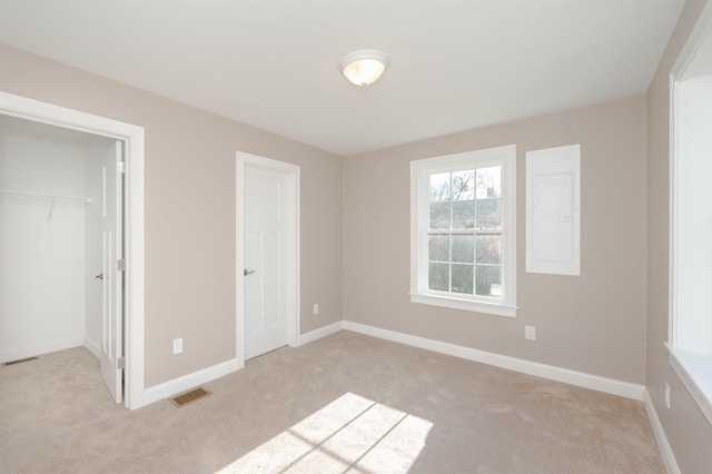 unfurnished bedroom with electric panel, light carpet, and a closet