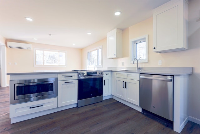 kitchen with a wall mounted air conditioner, white cabinets, sink, dark hardwood / wood-style floors, and stainless steel appliances