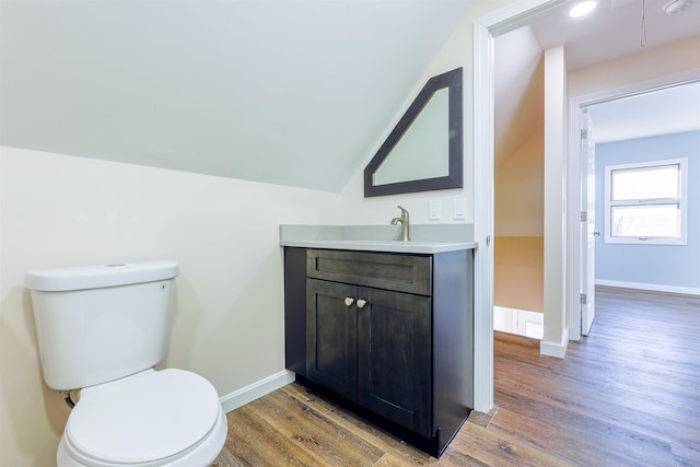 bathroom with toilet, wood-type flooring, vanity, and vaulted ceiling