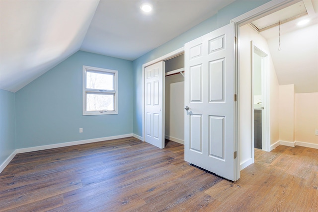 additional living space with hardwood / wood-style floors and lofted ceiling