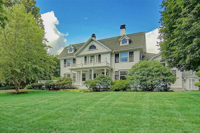 rear view of house featuring a porch, a balcony, and a yard