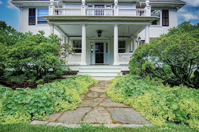 view of exterior entry featuring a porch and a balcony