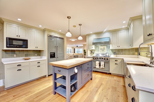 kitchen with built in appliances, decorative backsplash, extractor fan, and decorative light fixtures