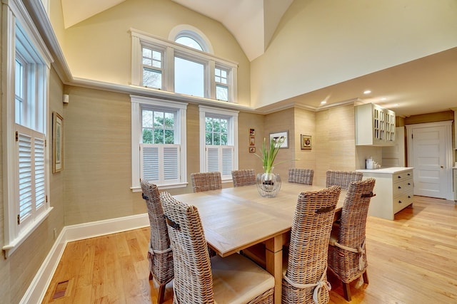 dining space with a towering ceiling and light hardwood / wood-style floors