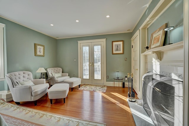 living area with hardwood / wood-style flooring, ornamental molding, and french doors