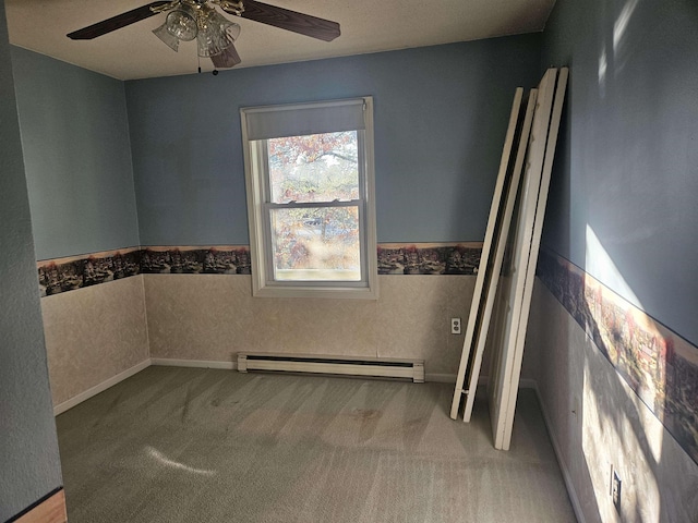 carpeted empty room with ceiling fan and a baseboard heating unit