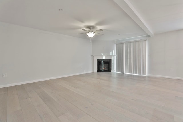 unfurnished living room with beam ceiling, a premium fireplace, ceiling fan, and light hardwood / wood-style floors