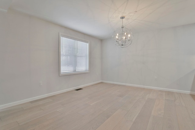 spare room featuring light hardwood / wood-style floors and a chandelier