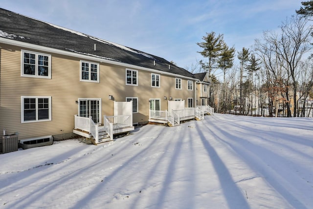 snow covered rear of property with a wooden deck and cooling unit