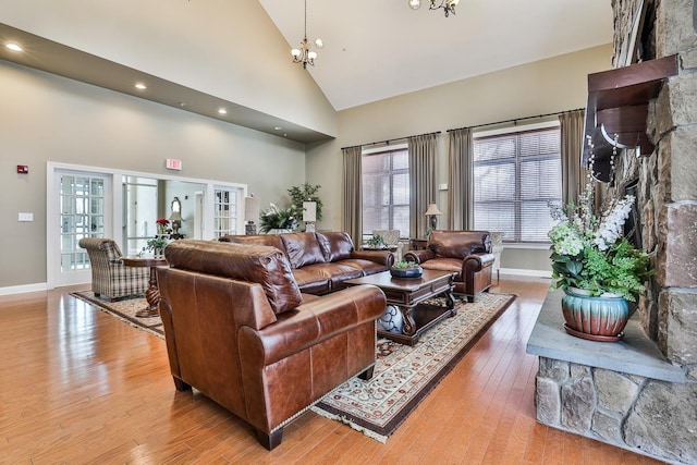 living room with light hardwood / wood-style floors, high vaulted ceiling, and an inviting chandelier