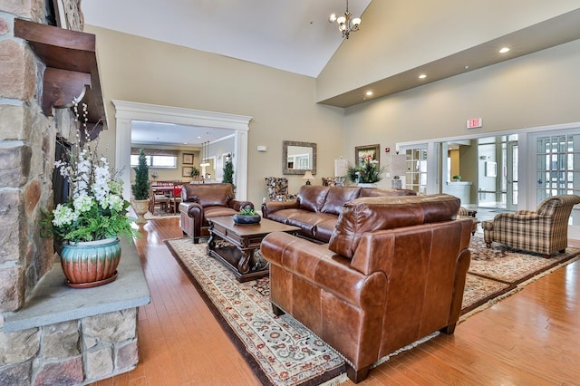 living room with a notable chandelier, light hardwood / wood-style floors, and high vaulted ceiling