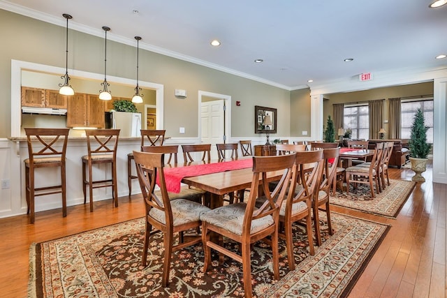 dining room featuring wood-type flooring, ornamental molding, and ornate columns