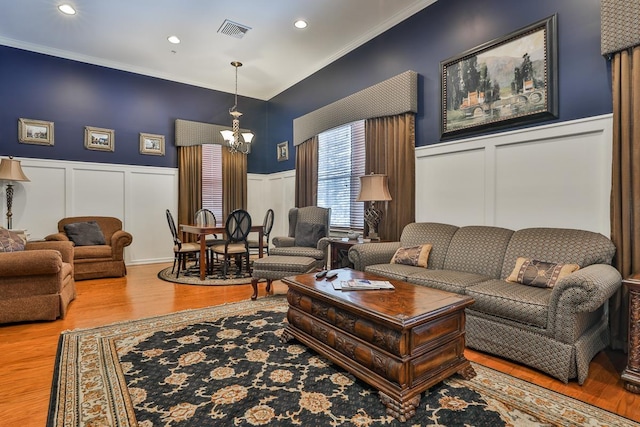 living room with hardwood / wood-style flooring, ornamental molding, and a chandelier